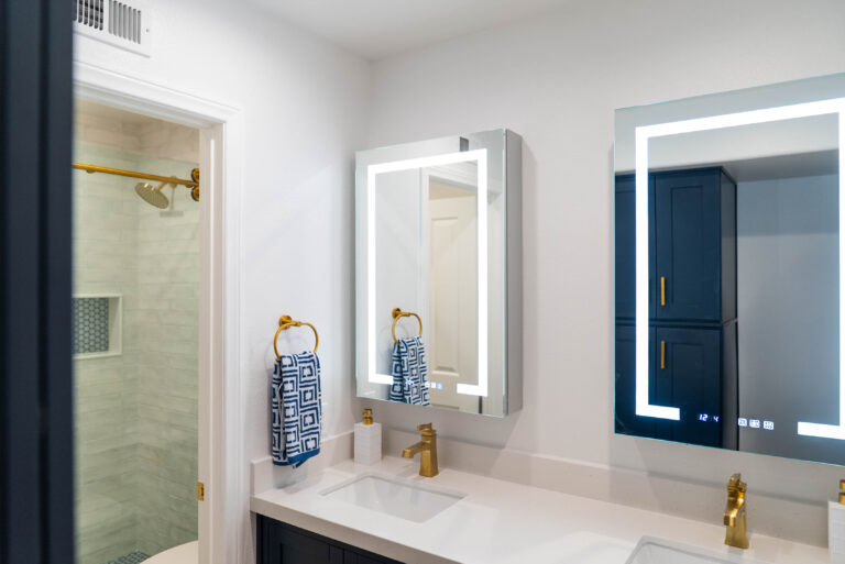 A bathroom featuring two mirrors above a sink and a spacious shower area, showcasing modern design elements.
