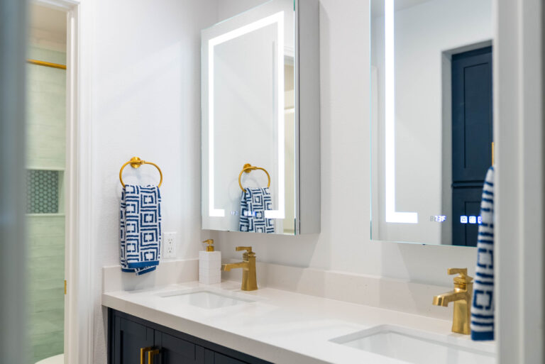 A well-lit bathroom with two stylish mirrors and a glass shower, emphasizing a clean and contemporary aesthetic.